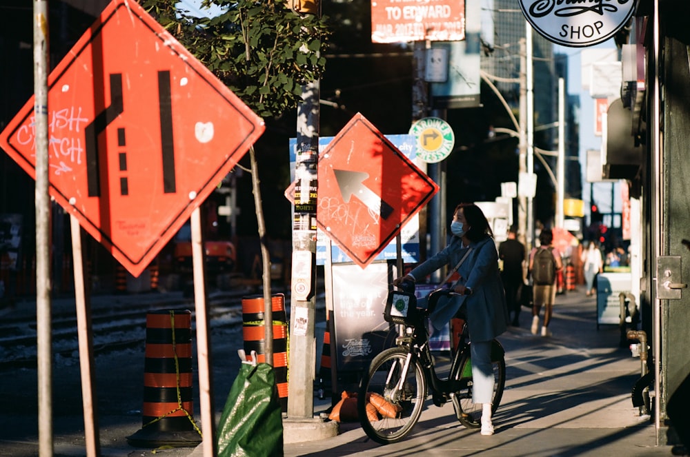 a woman riding a bike down a street next to traffic signs