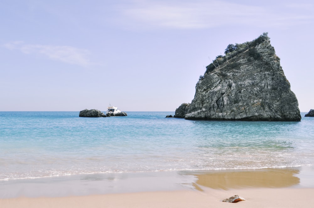 a beach with a rock formation in the water