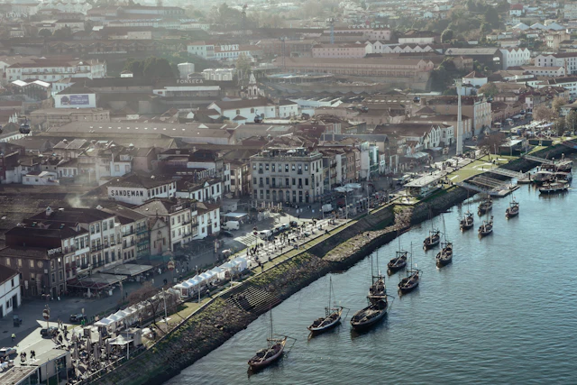 Traditional rabelo wine boats moored along the Vila Nova de Gaia riverside quay lined with cafes.