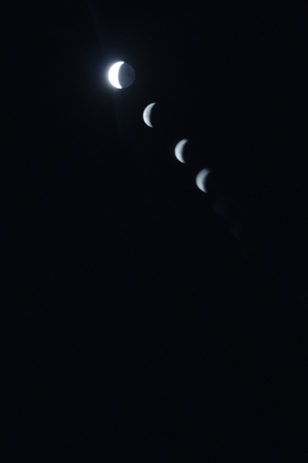 a line of phases of the moon in the dark sky