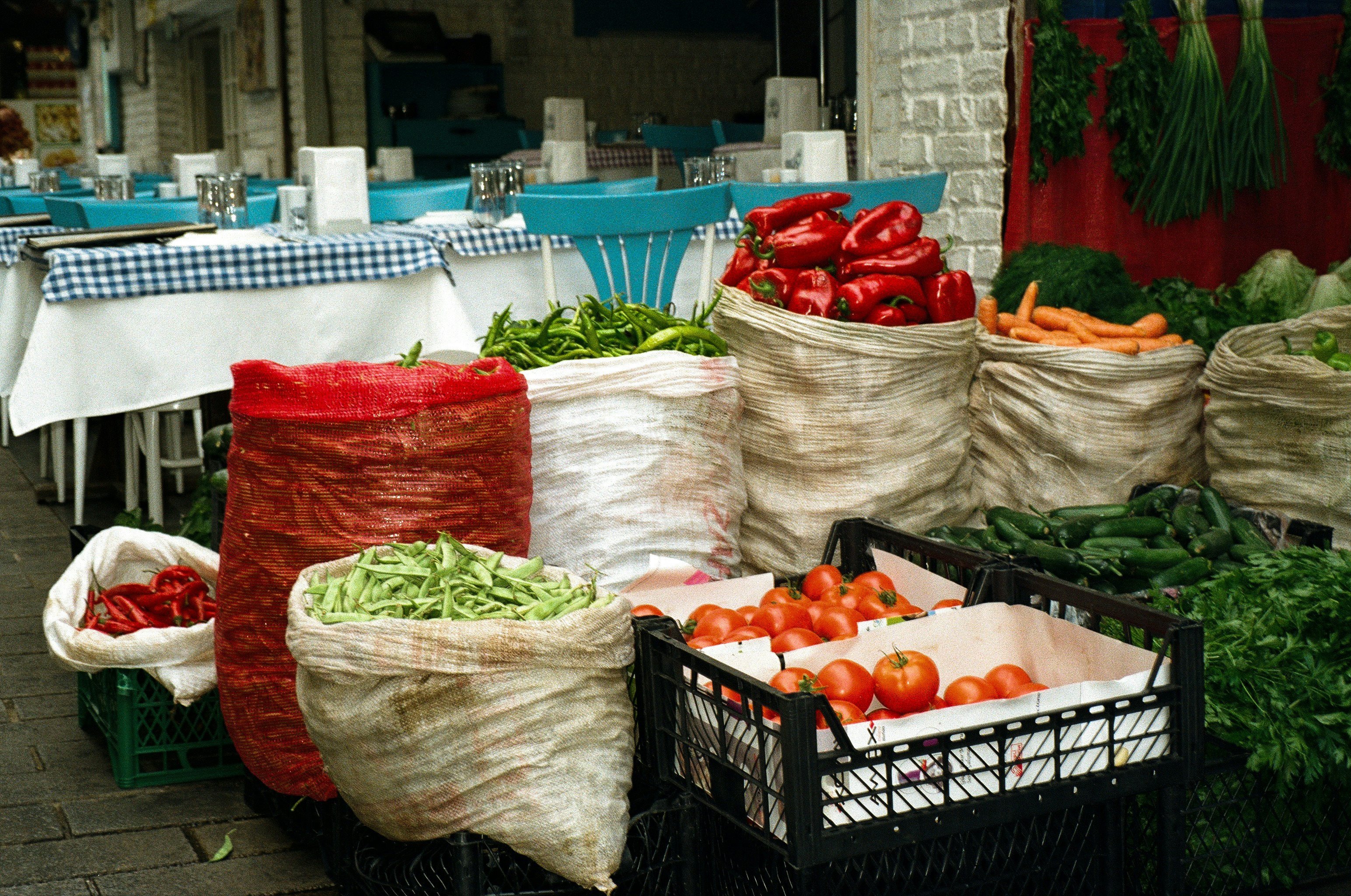 Mutfak tezgahında taze sebzelerle yemek hazırlayan ve bütçe planlaması yapan bir kişinin elleri, yanında hesap makinesi ve alışveriş listesi.
