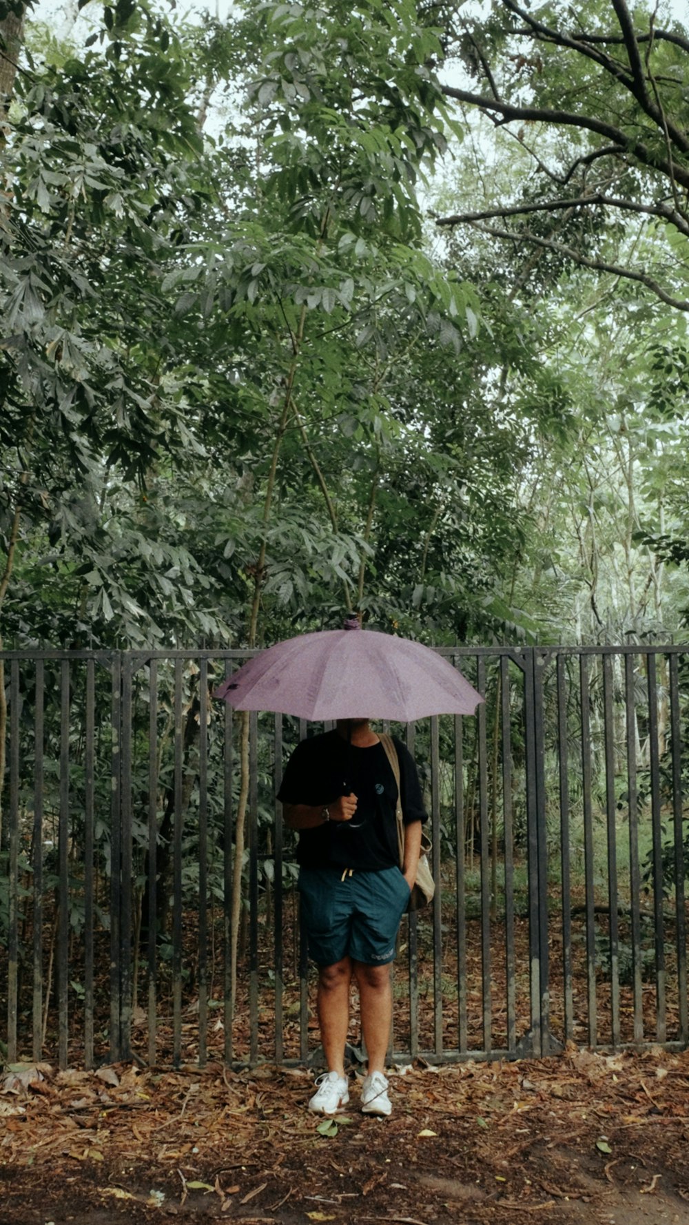 a person holding an umbrella in front of a fence