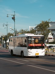 a white bus driving down a street next to a traffic light