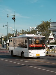 a white bus driving down a street next to a traffic light