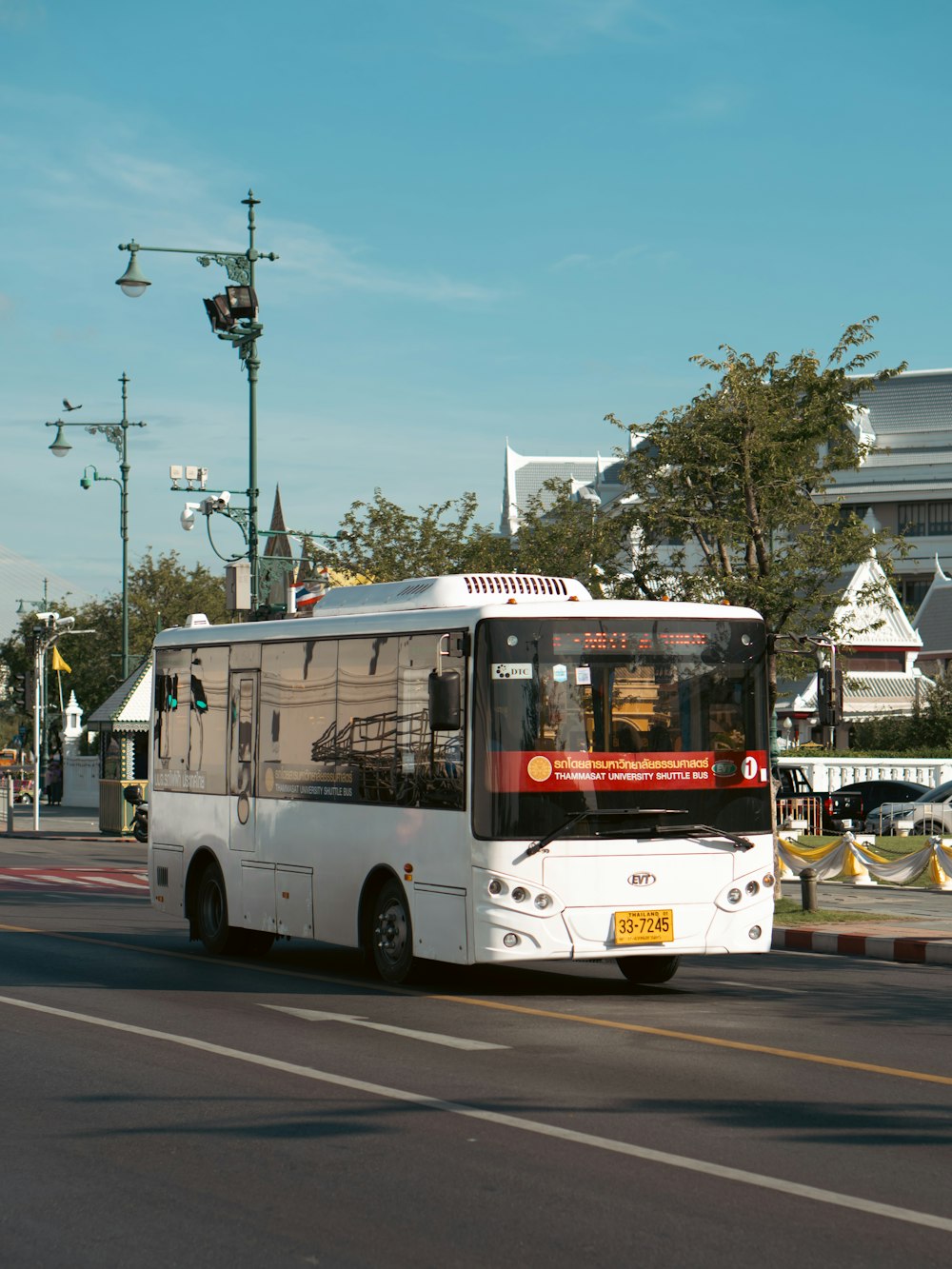 a white bus driving down a street next to a traffic light