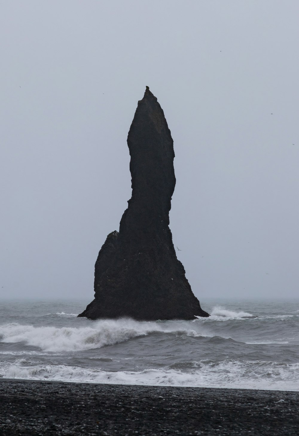 a large rock sticking out of the ocean