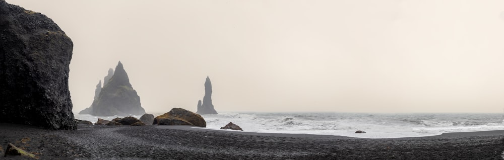 a rocky beach with a large rock sticking out of the water