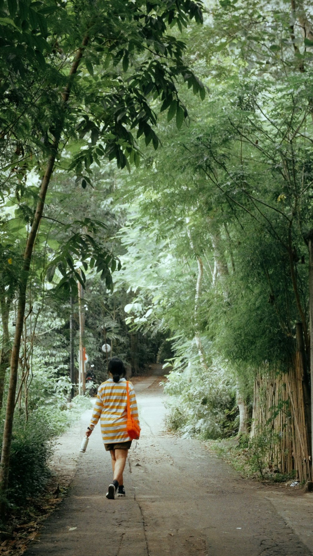 a woman walking down a dirt road in the woods