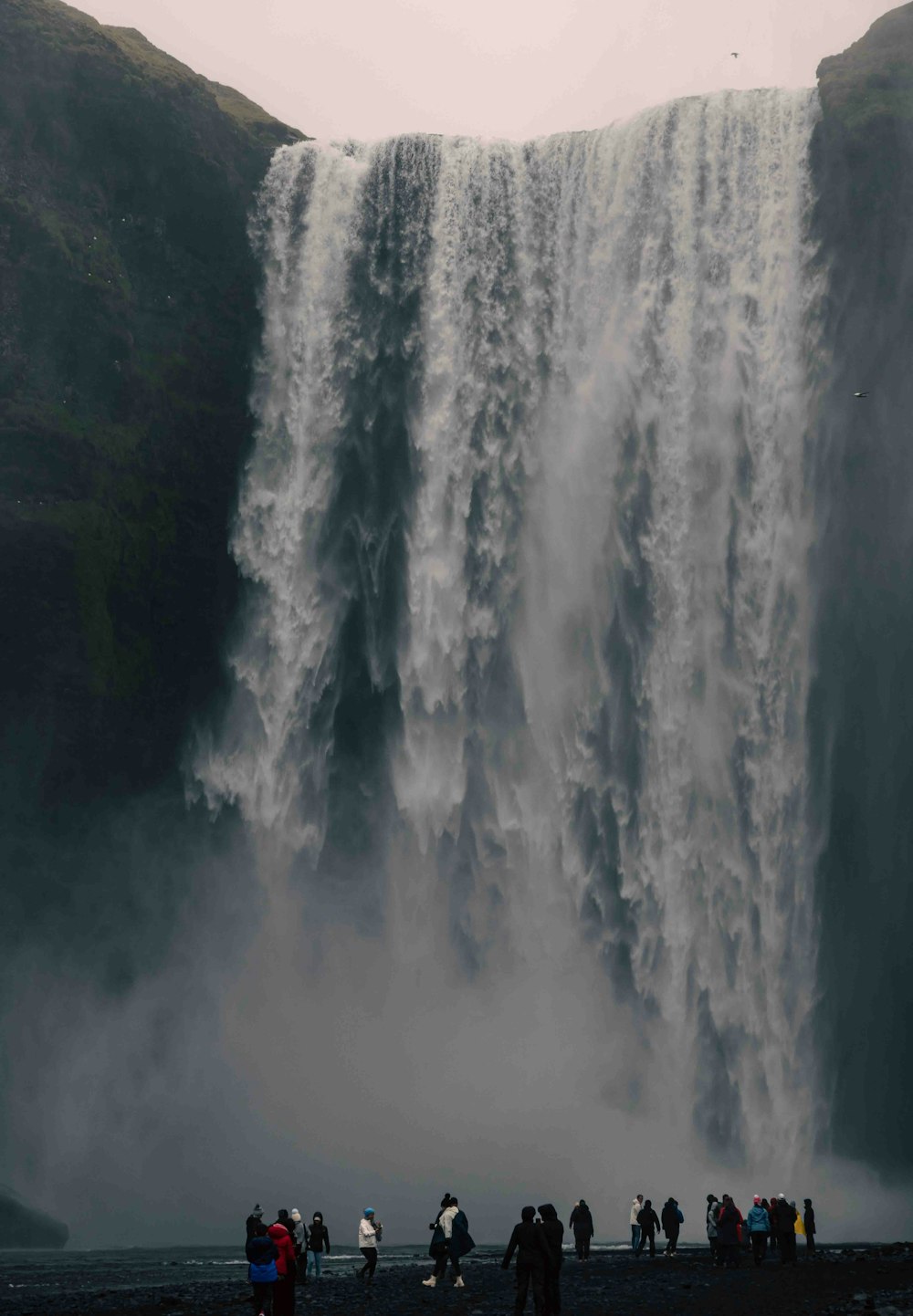 a group of people standing in front of a waterfall