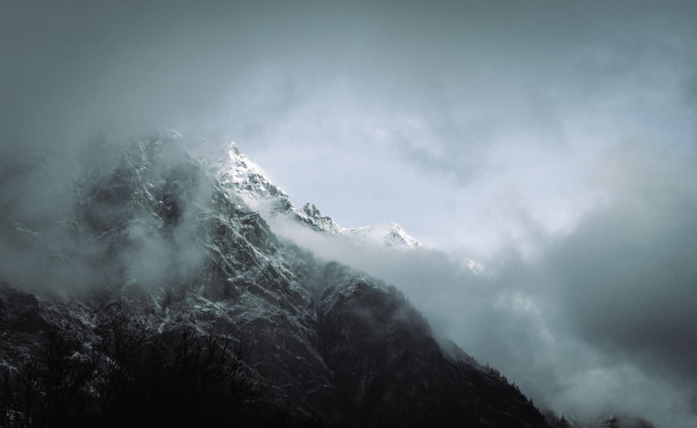 a very tall mountain covered in snow under a cloudy sky