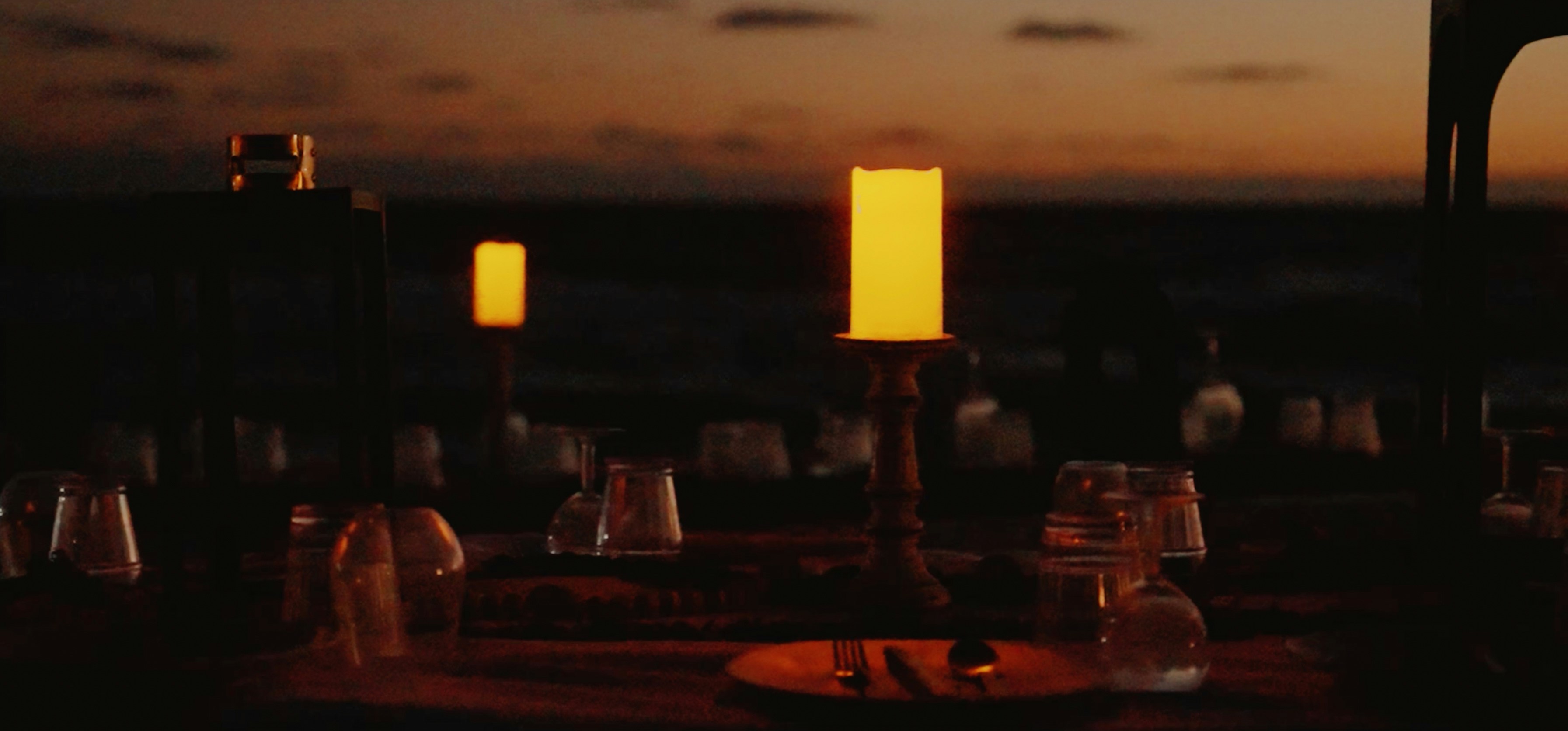 Candle glowing on a table at dusk