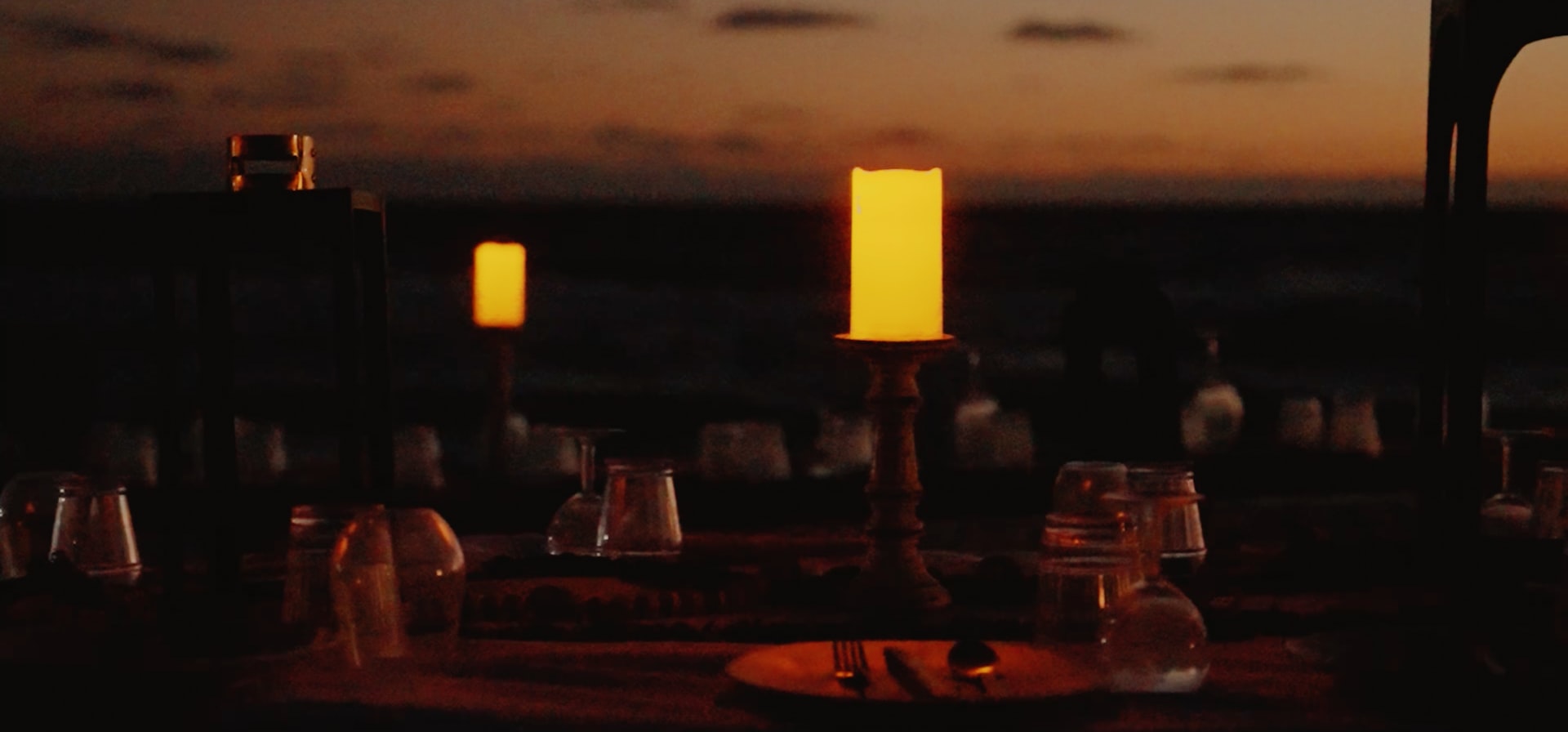 a table topped with candles and glasses on top of a wooden table