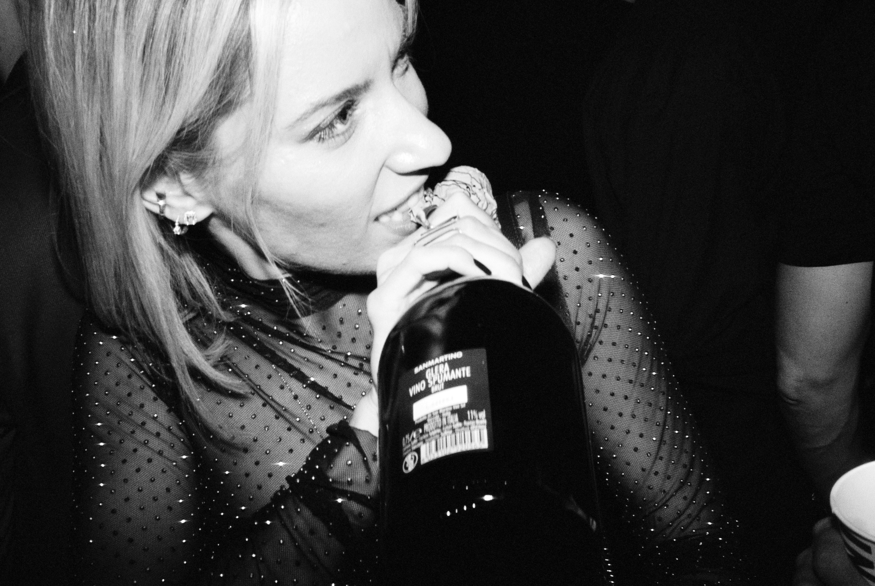 a black and white photo of a woman drinking from a bottle