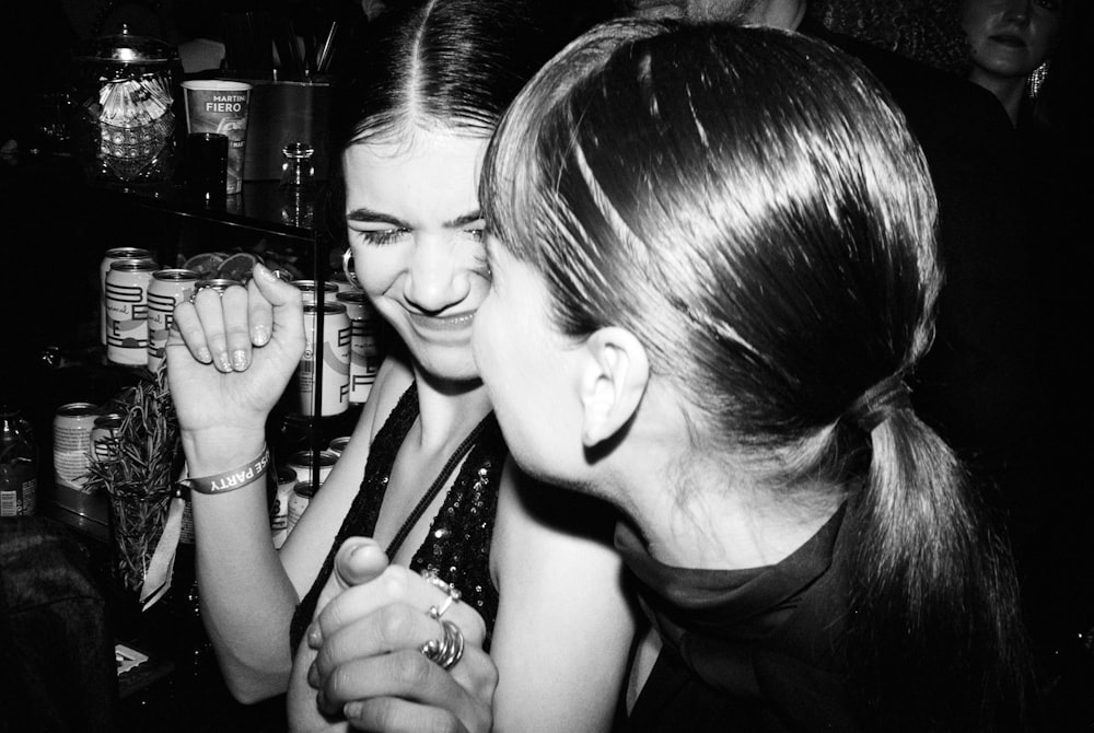 two young women are laughing together at a bar