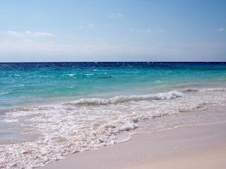 a sandy beach with a wave coming in to shore