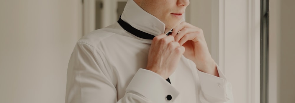 a woman in a white shirt adjusting her collar