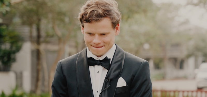 a man in a tuxedo smiles at the camera