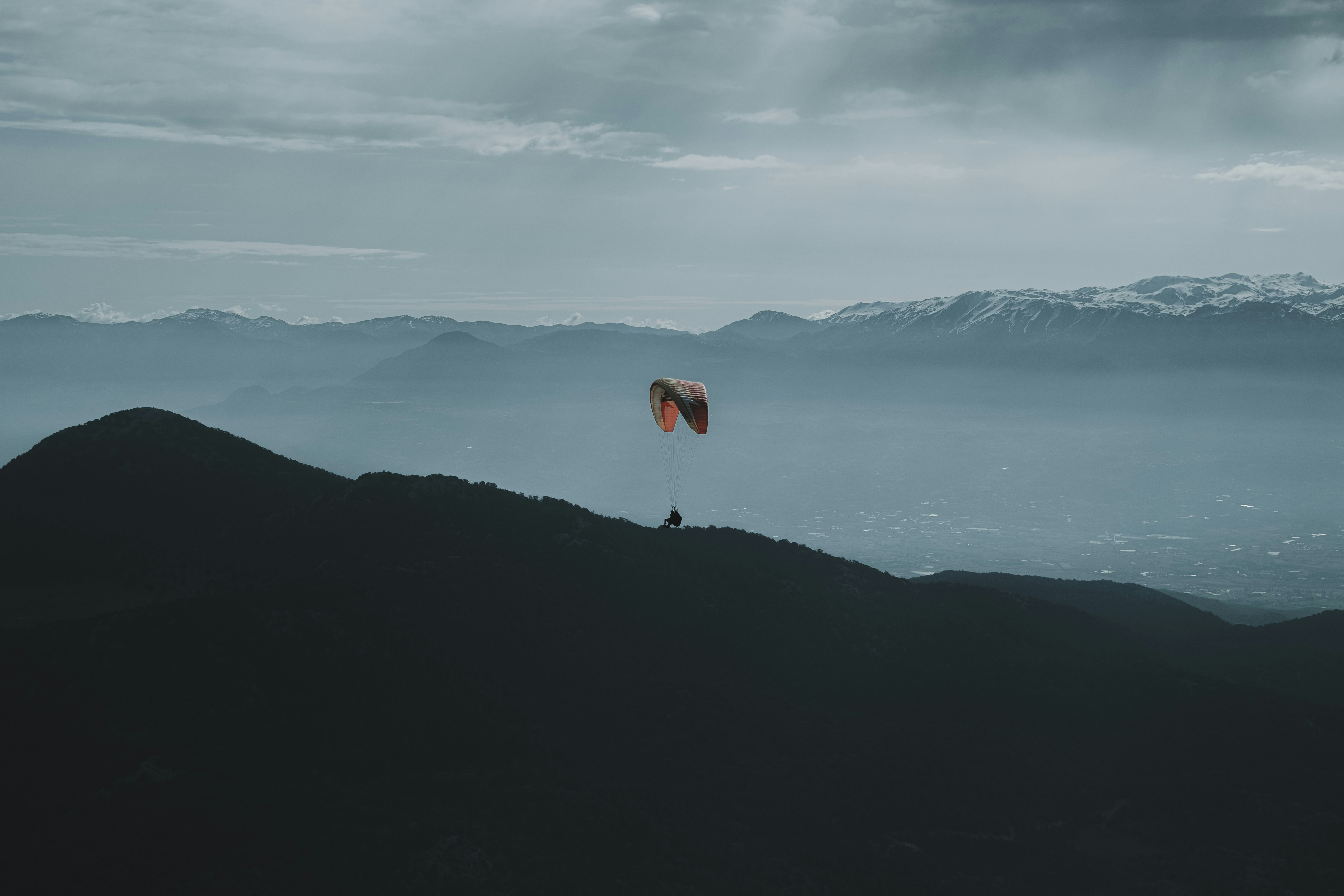 a paraglider is flying over a mountain range