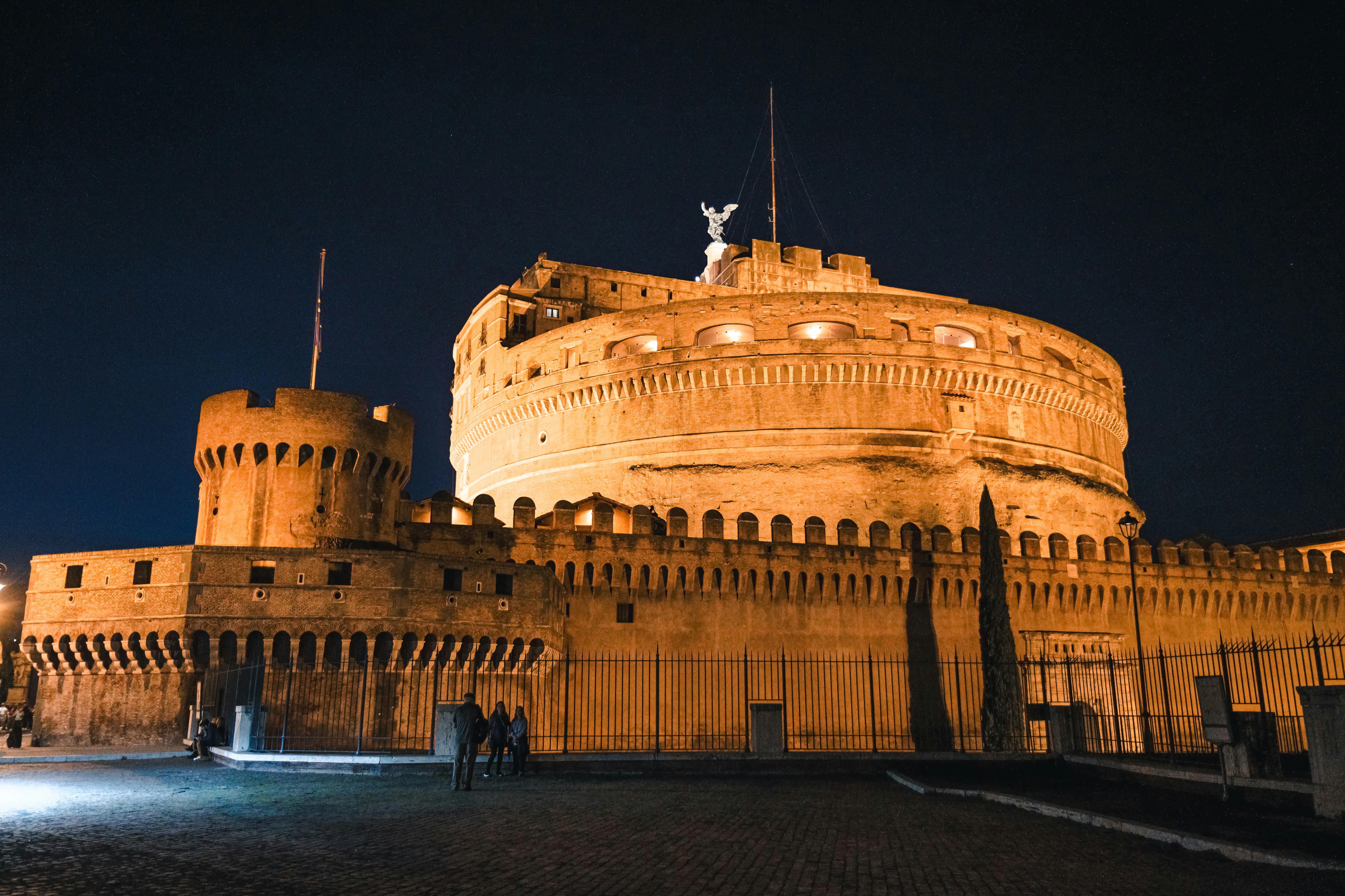 two people standing in front of a castle at night