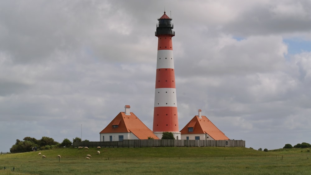 a red and white lighthouse on top of a hill