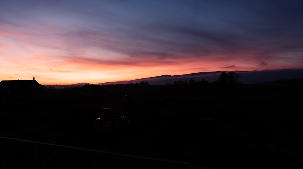 a sunset with clouds and a house in the distance