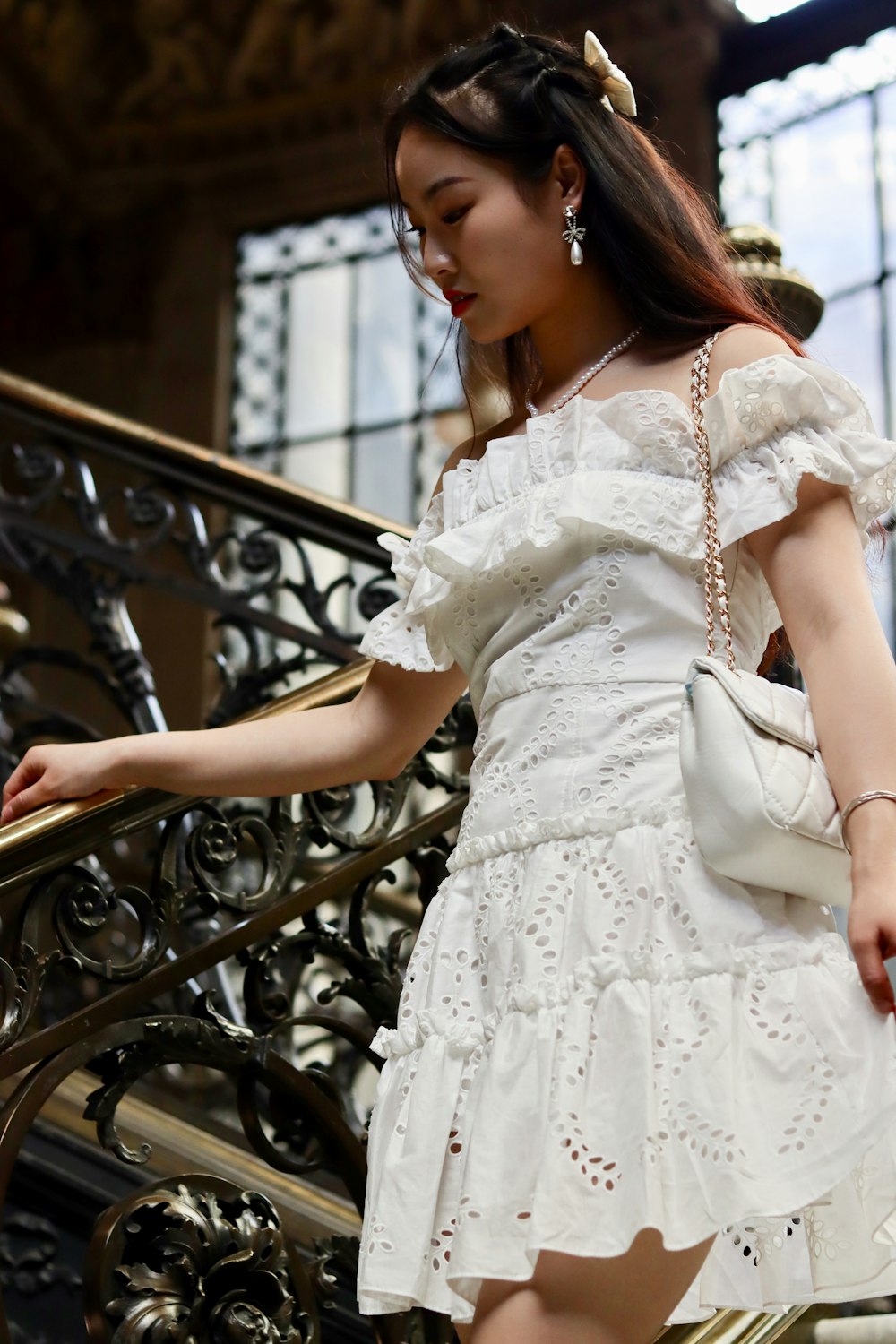 Une femme vêtue d’une robe blanche descend un escalier