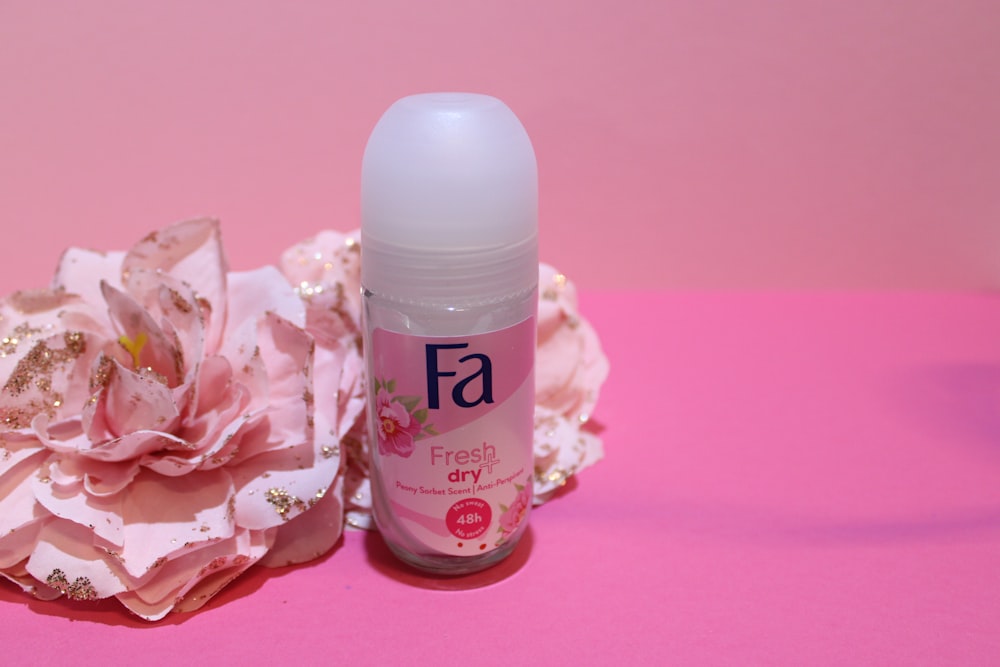 a close up of a bottle of deodorant next to a flower