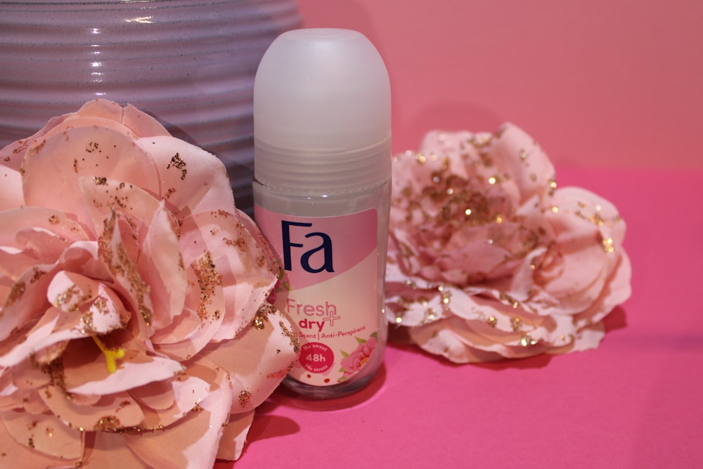 a close up of a bottle of deodorant next to a flower