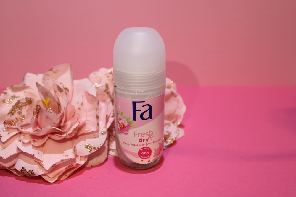 a close up of a bottle of deodorant on a pink surface