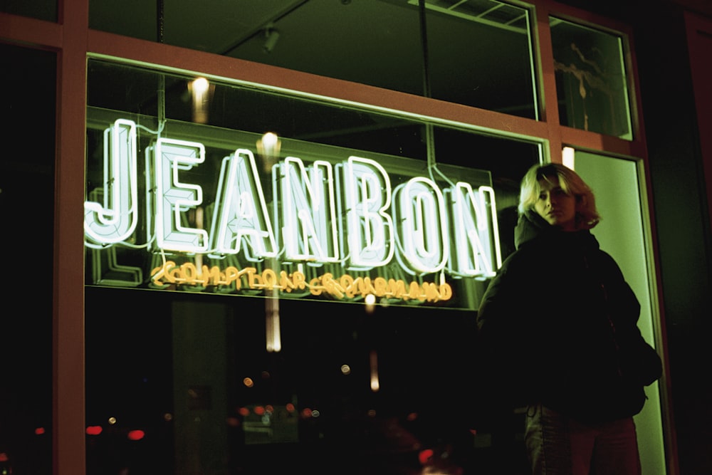 a woman standing in front of a neon sign