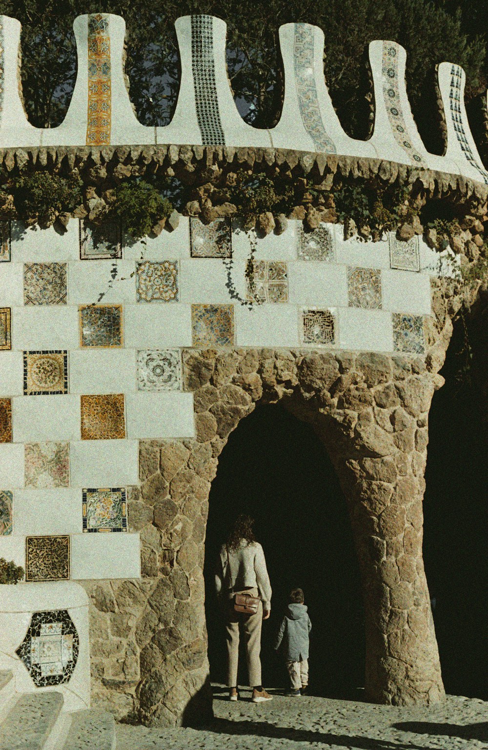 a man and a child standing in front of a stone wall