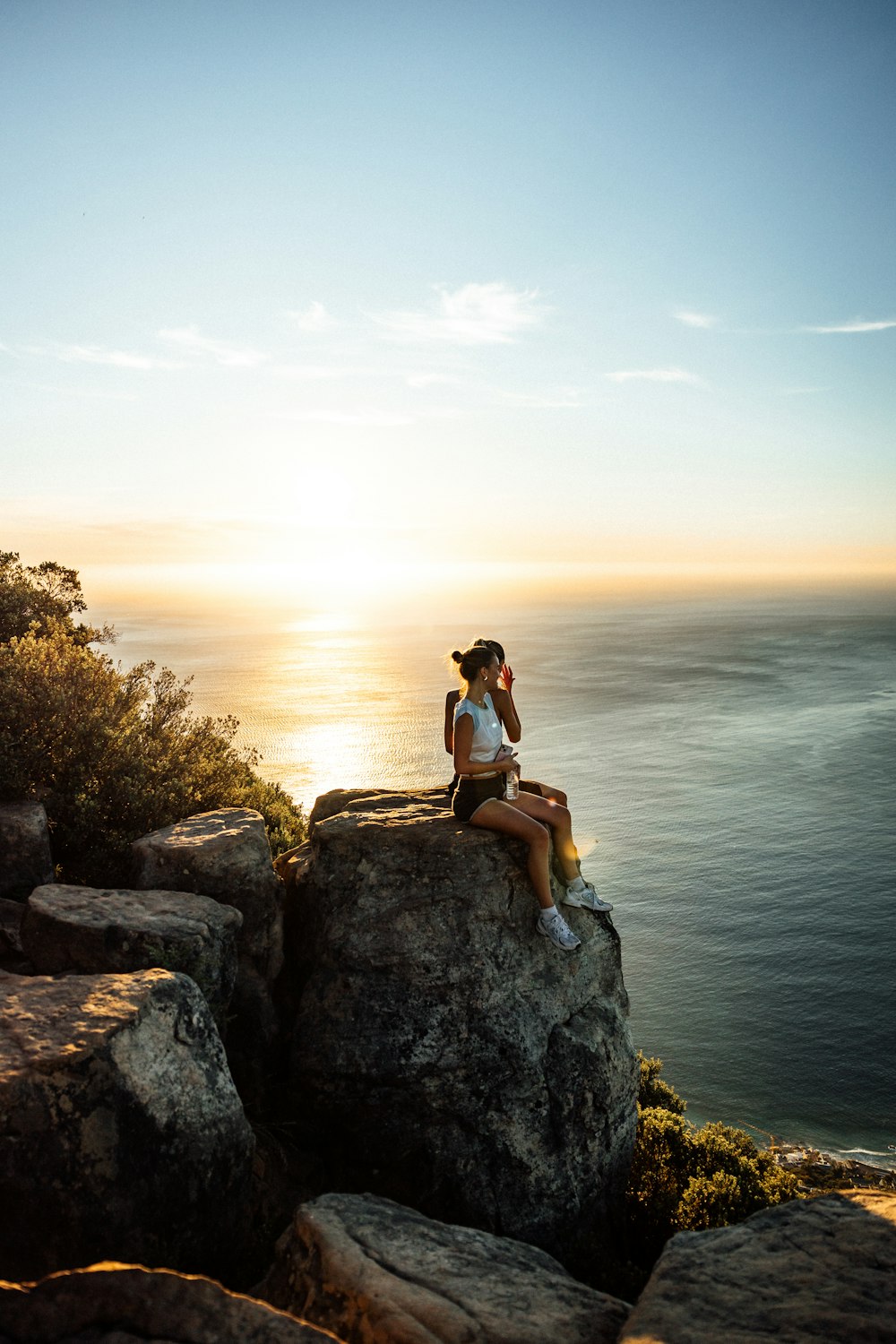 a woman sitting on top of a rock next to the ocean