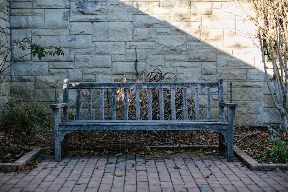 a wooden bench sitting in front of a brick wall