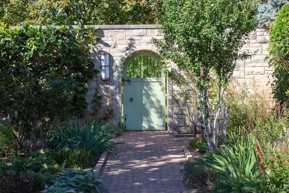 a garden with a green door surrounded by trees