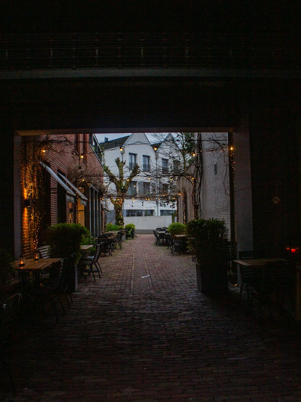 a dark alley way with tables and chairs