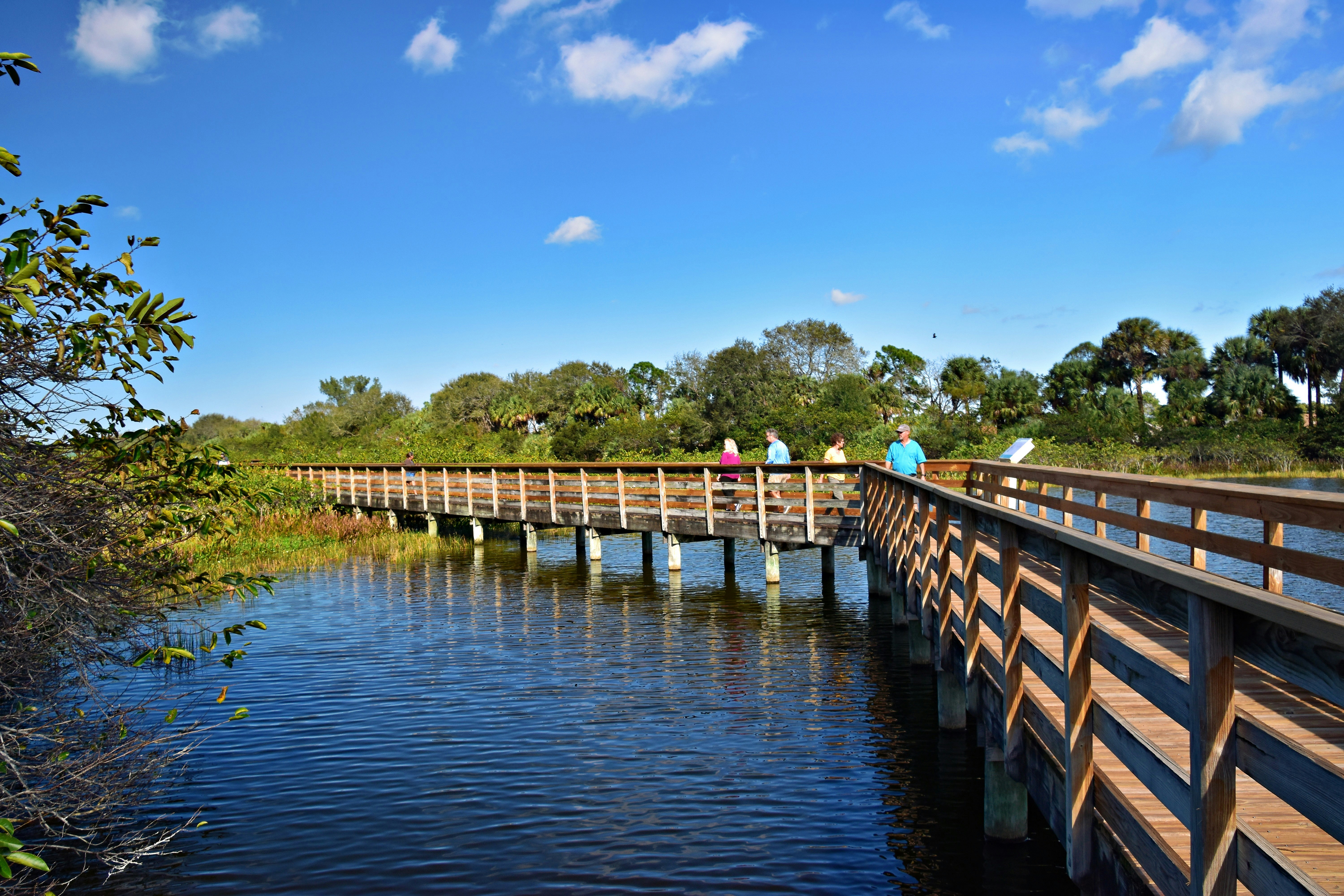 people walking across a bridge over a body of water
