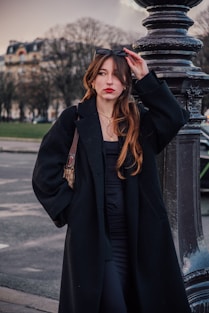 a woman leaning against a pole with her hand on her head