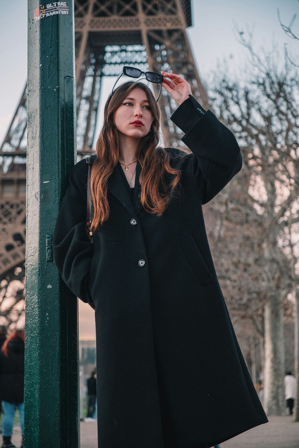 a woman standing next to a pole in front of the eiffel tower