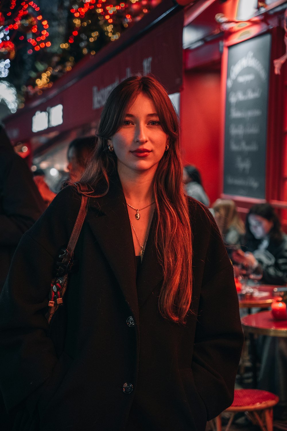 a woman in a black coat standing in a restaurant