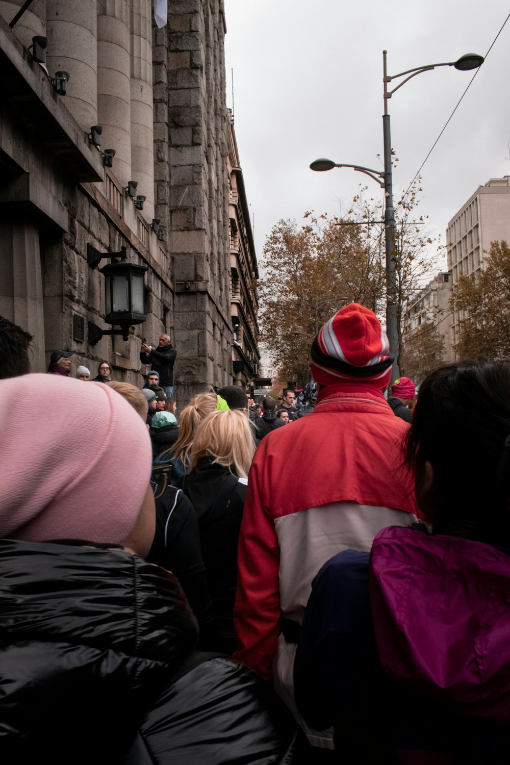 a crowd of people walking down a street next to tall buildings