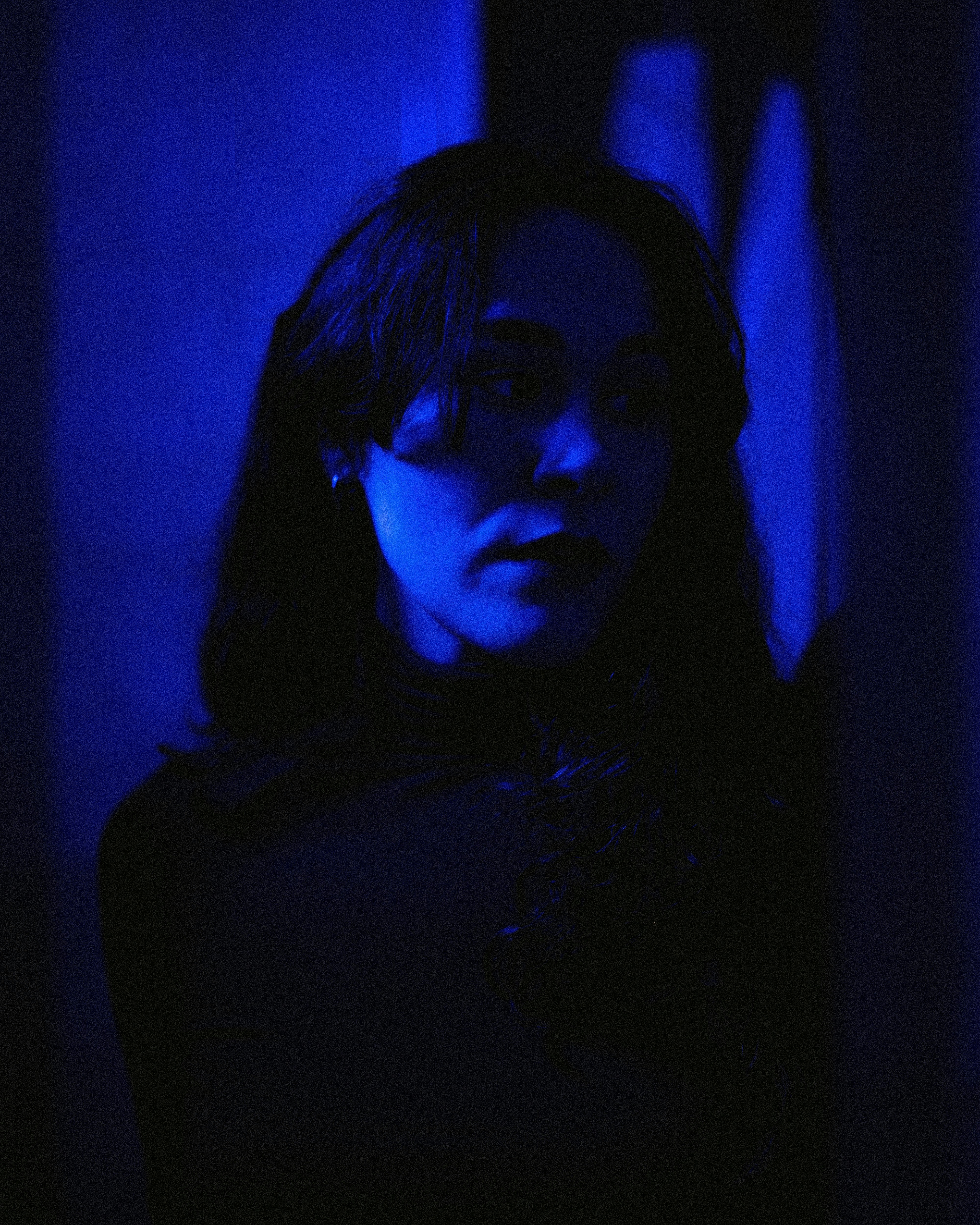 a woman standing in a dark room with a blue light
