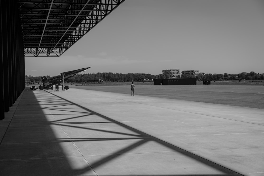 a black and white photo of a person standing under a roof