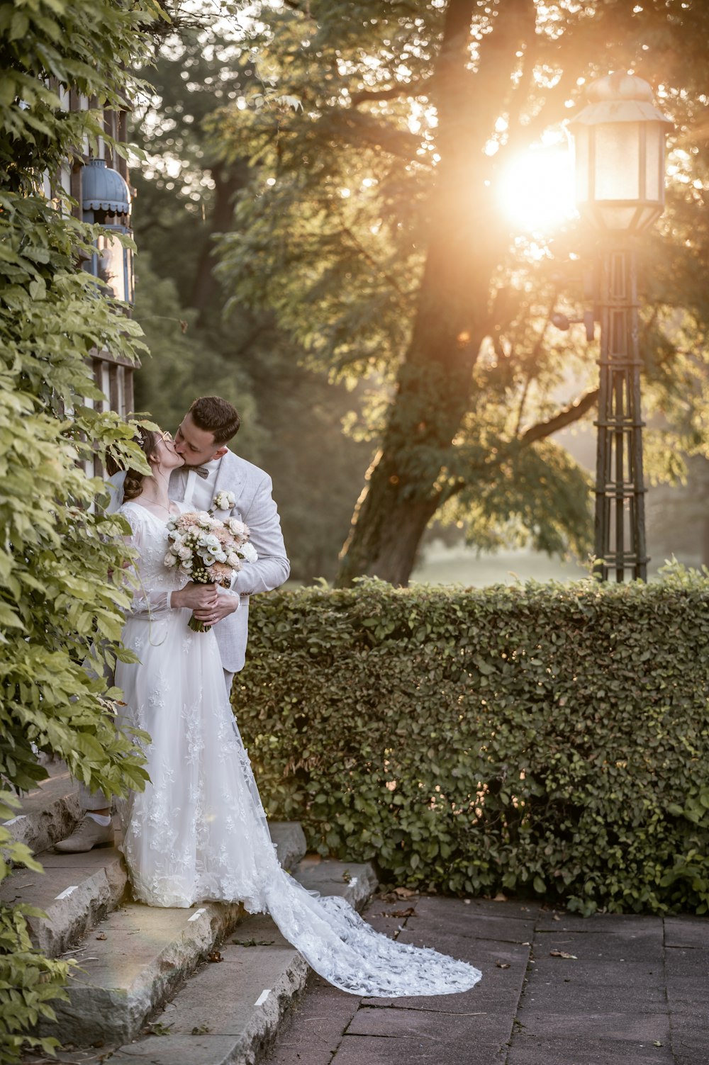 a bride and groom kissing in front of a light post