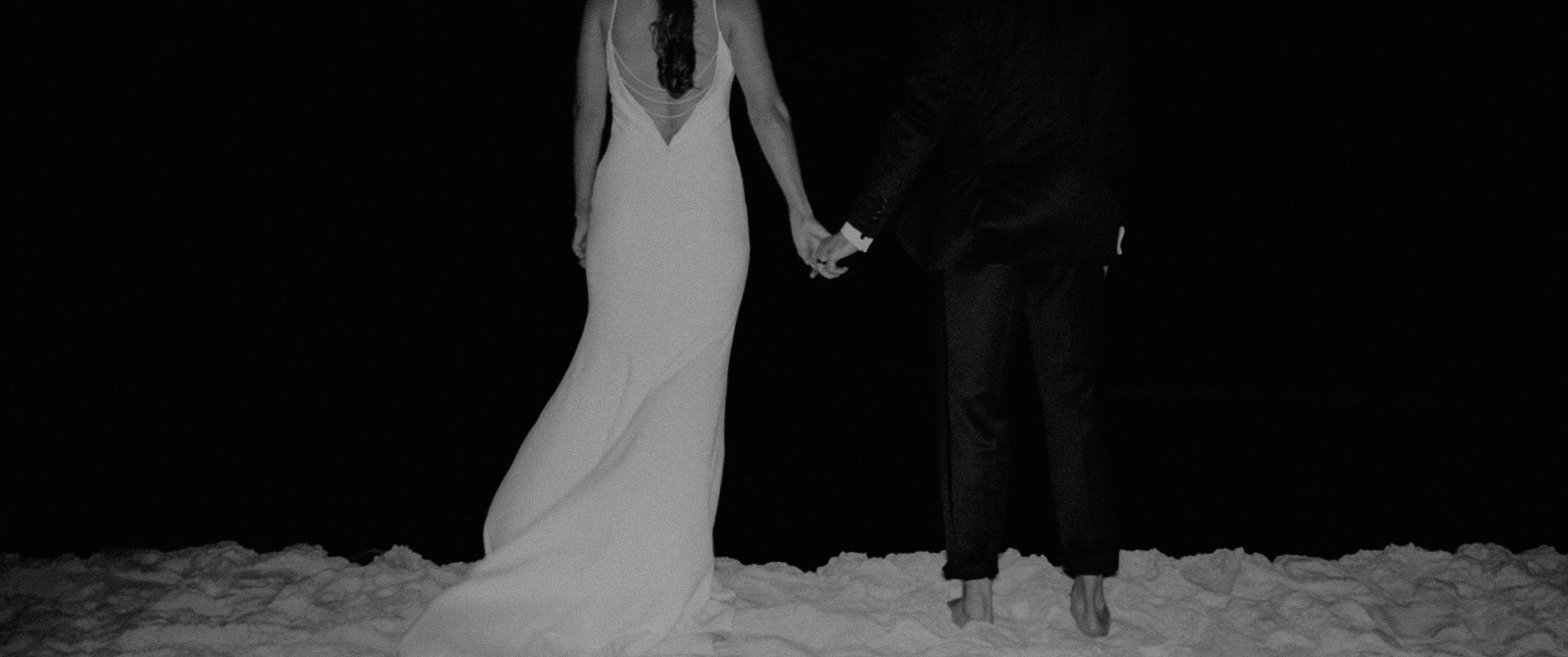 a bride and groom holding hands in the snow