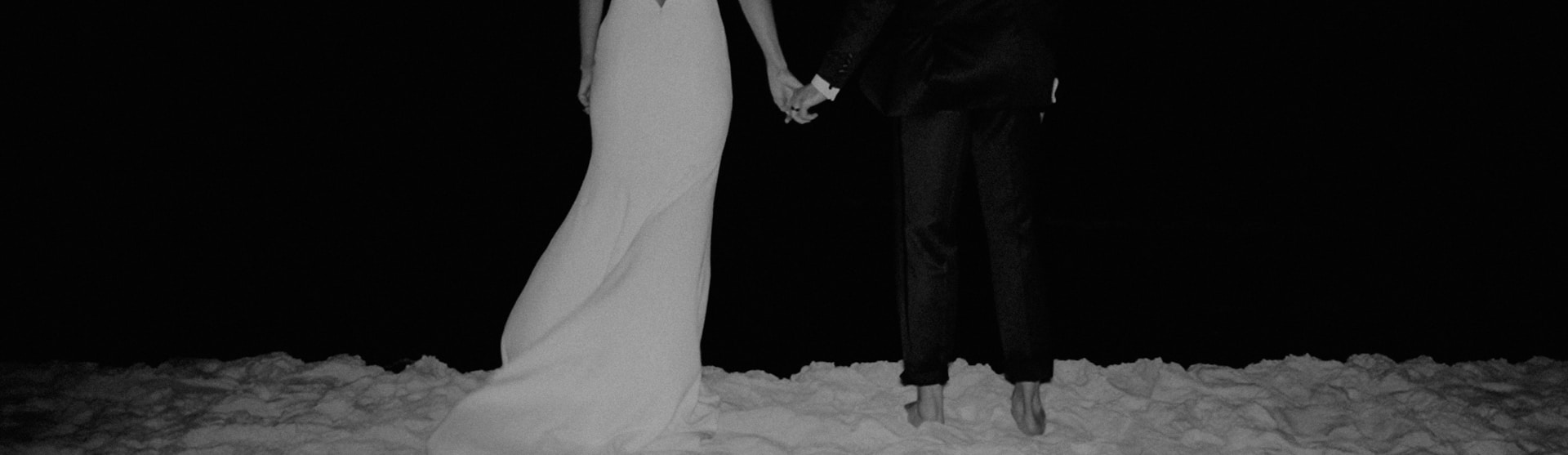 a bride and groom holding hands in the snow