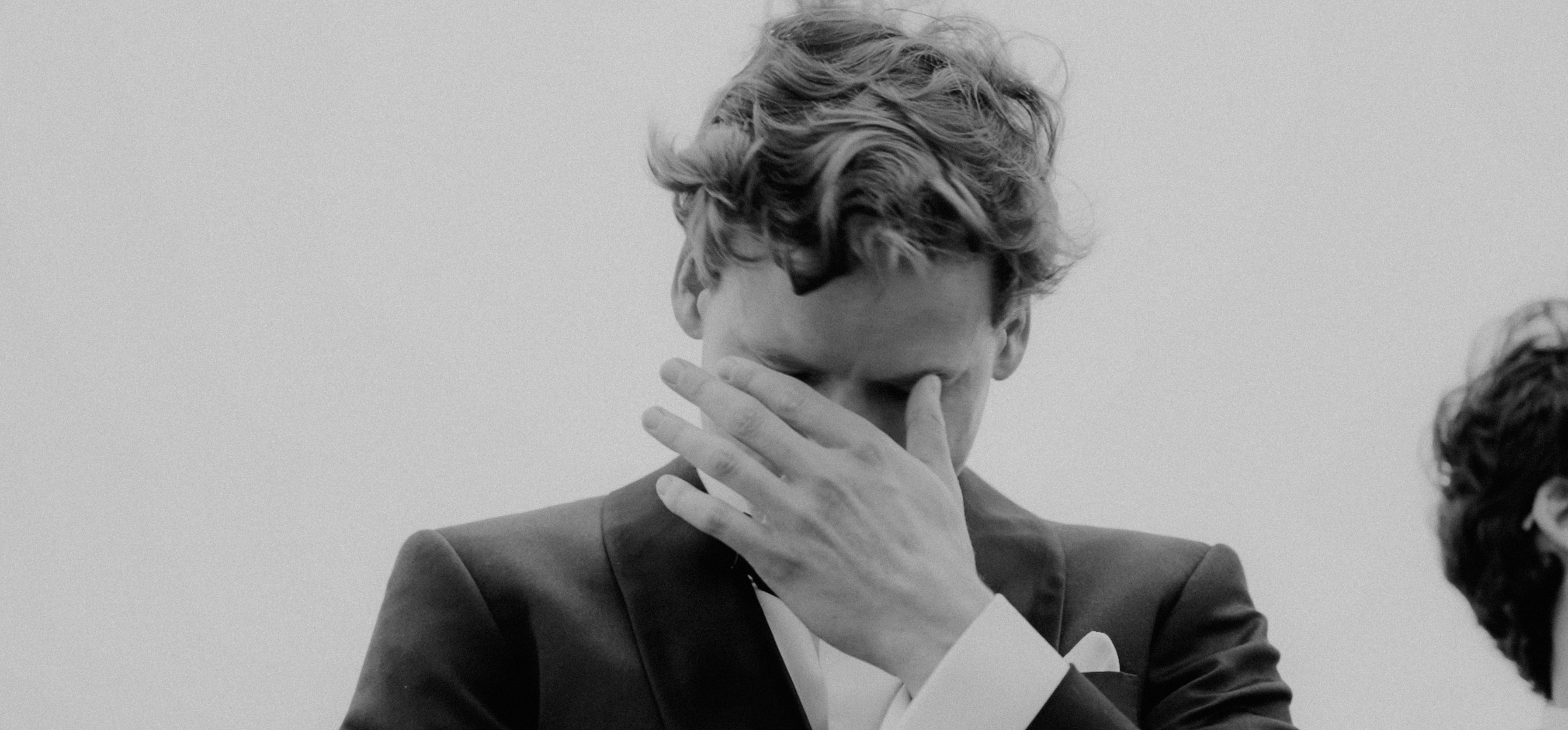 a black and white photo of a man covering his face (Photo by 550Park Luxury Wedding Films on Unsplash)