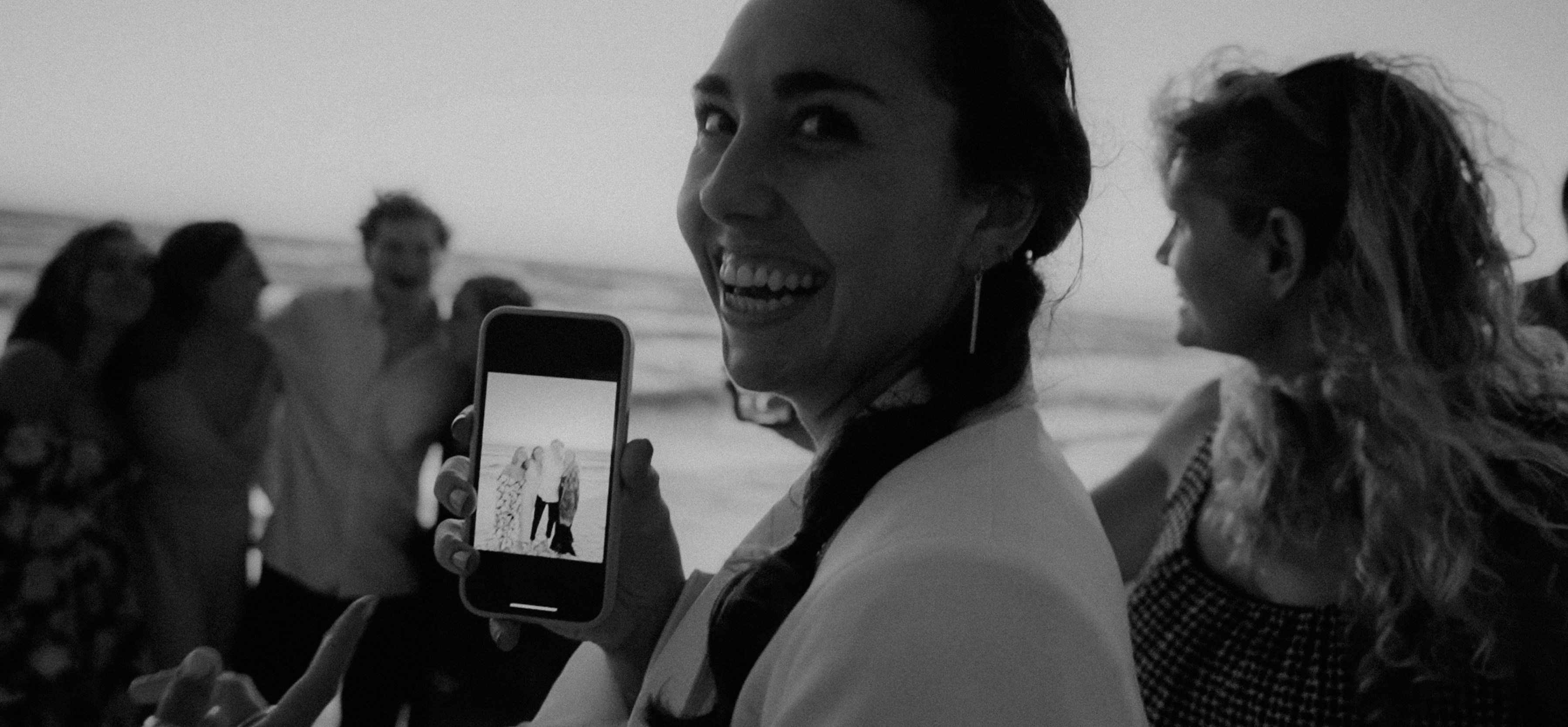 a woman holding up a cell phone in front of a group of people