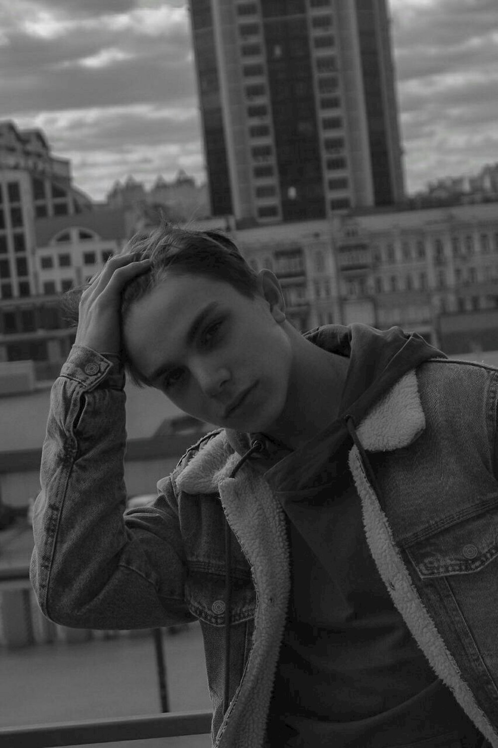 a man in a denim jacket leaning on a railing