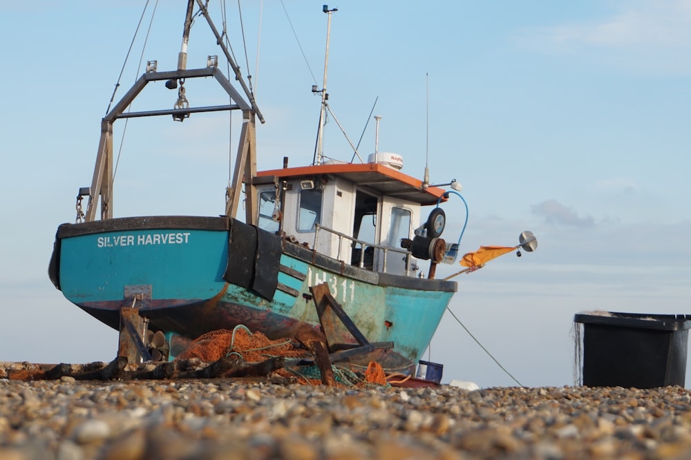 a blue and white boat sitting on top of a beach