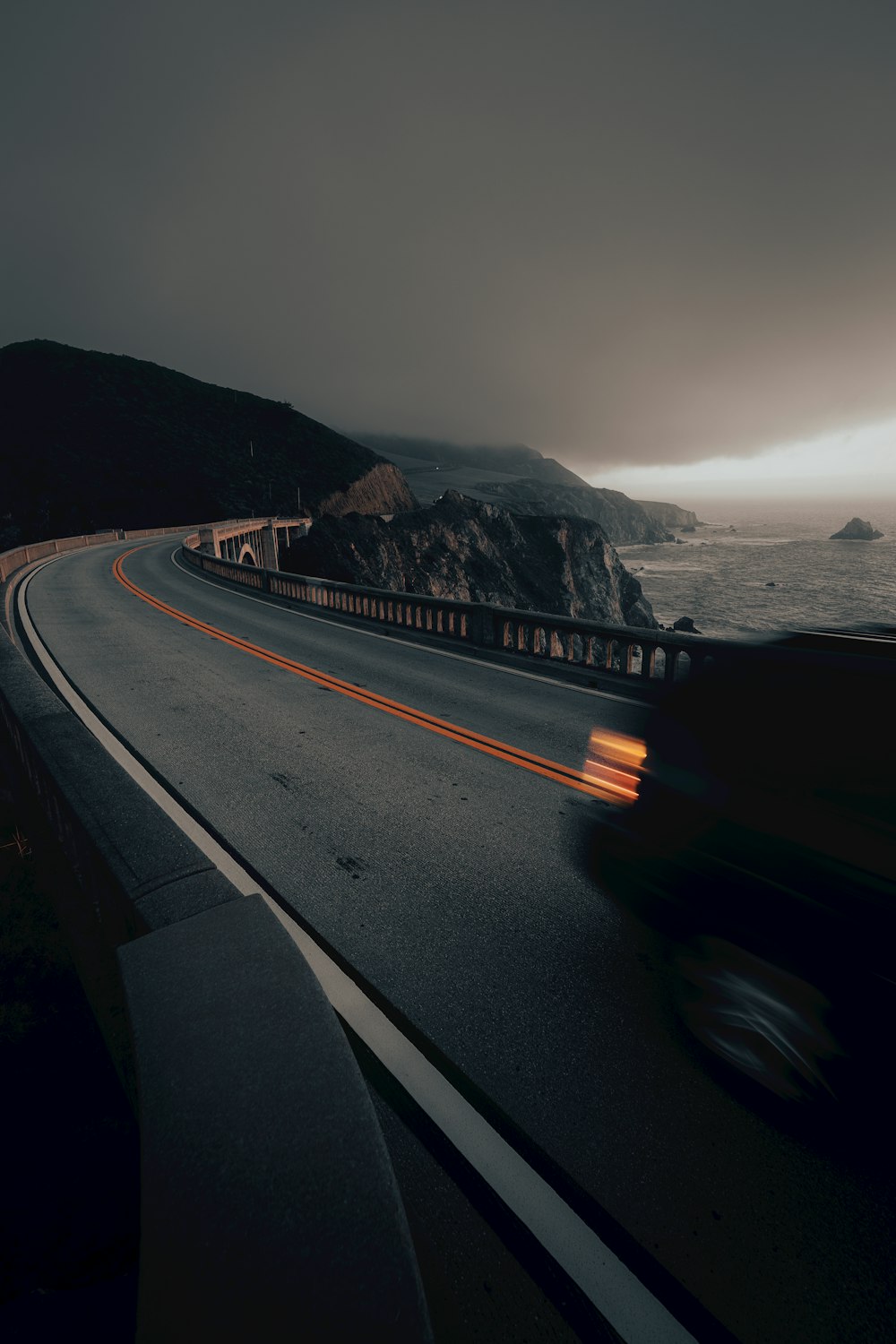 a car driving down a road next to the ocean